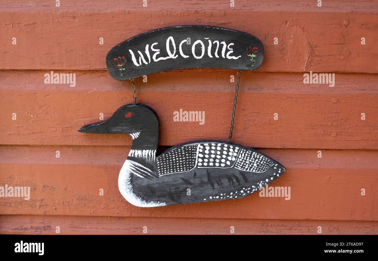 Letrero de bienvenida de la cabaña con un pájaro de lomo de madera pintado artísticamente. Danbury Wisconsin WI Estados Unidos Foto de stock