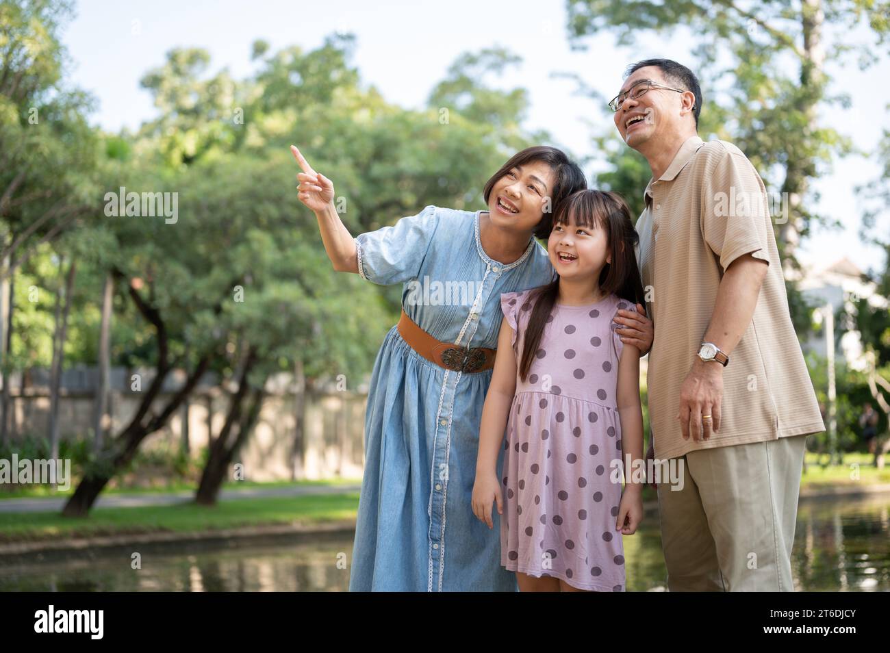 Los abuelos asiáticos amables y felices se divierten con su nieta, paseando por el parque público en un día brillante juntos. Familia feliz, fa Foto de stock