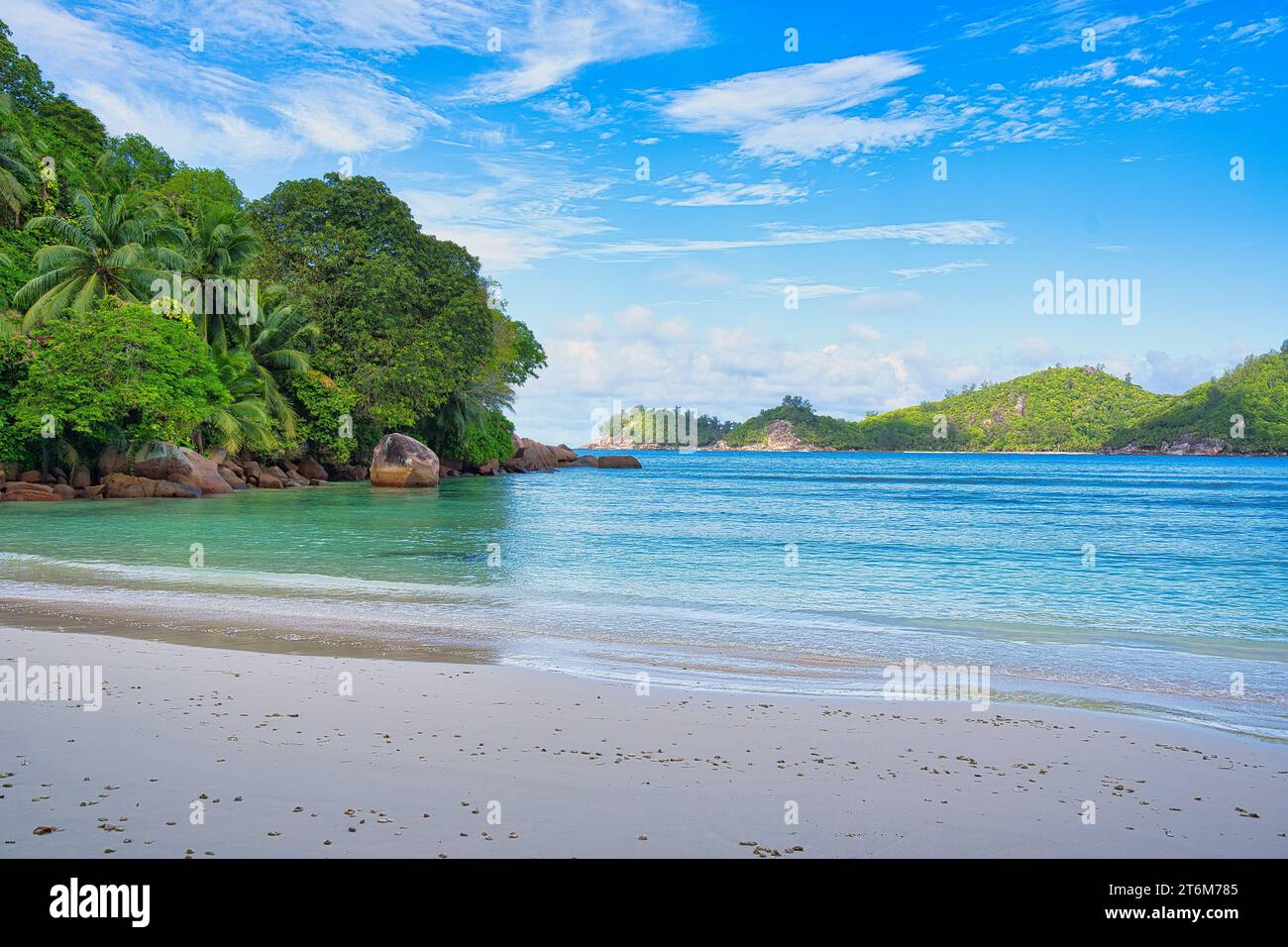 Soleada, playa de arena blanca, enormes rocas de granito en la playa Baie Lazare, Mahe, Seychelles Foto de stock