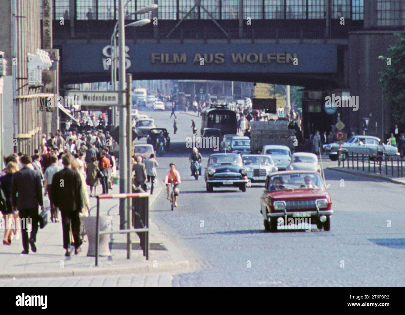 Berlín, Ostberlin GER, Berlin,20230101, Aufnahme ca. 1976, historische Stadtansicht, in Ostberlin, Foto von der Friedrichstrasse / am Weidendamm, mit dem Bahnhof, Berufsverkehr, Menschen auf den Gehwegen und Autoverkehr auf der Strasse, die Richtung S-Bahnhof unterwegs sind, Beschriftung, Werbung mit 20230101 1976 vista histórica de la ciudad, en Berlín Oriental, foto de Friedrichstrasse am Weidendamm, con la estación de tren, el tráfico de horas punta, la gente en las aceras y el tráfico de coches en la calle, en dirección Foto de stock