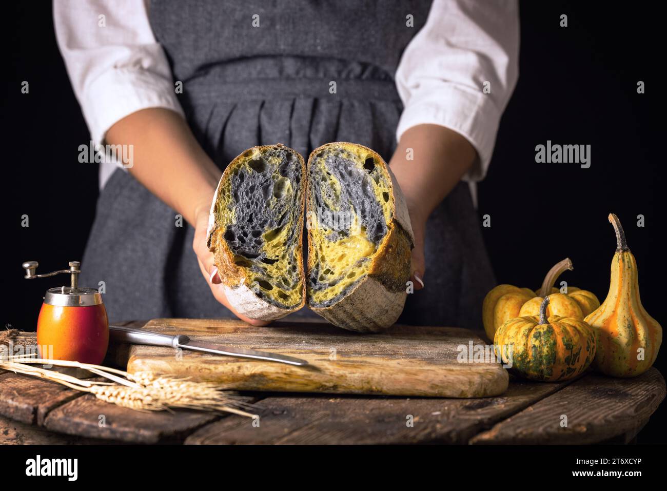 Masa madre casera activado carbón negro pan con calabaza horno de cúrcuma horneado y ama de casa mujer panadero con comida de otoño, estilo rústico antiguo Foto de stock