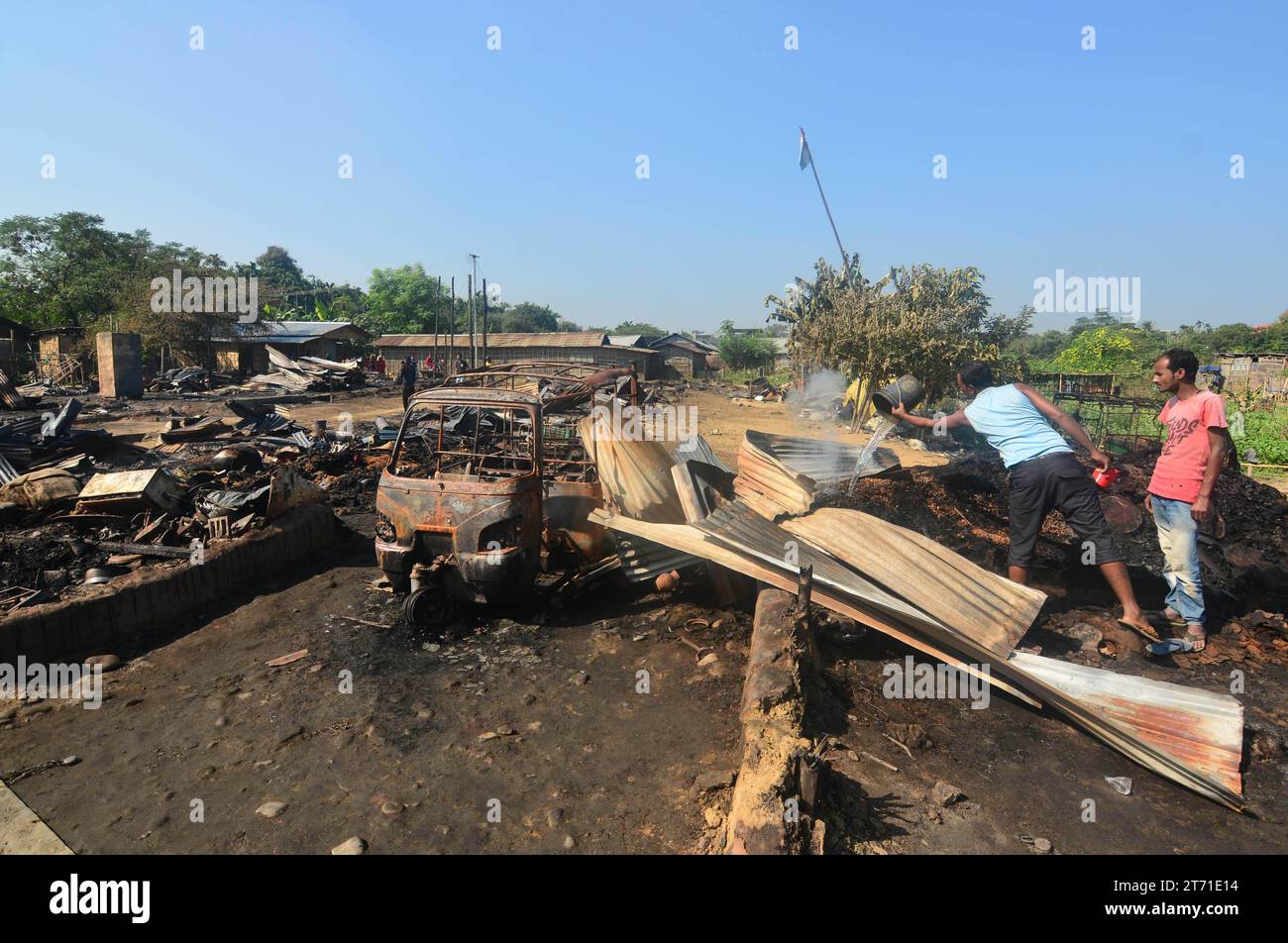 Dimapur, India: 13 de noviembre de 2023: Los residentes salpican agua para dosificar el fuego restante después de un infierno en la noche de Diwali, la celebración del Festival Hindú de la Luz, que destruyó al menos 50 casas matando a 5 personas en Naharbari en Dimapur, India, estado nororiental de Nagaland. Crédito: Caisii Mao/Alamy Live News Foto de stock