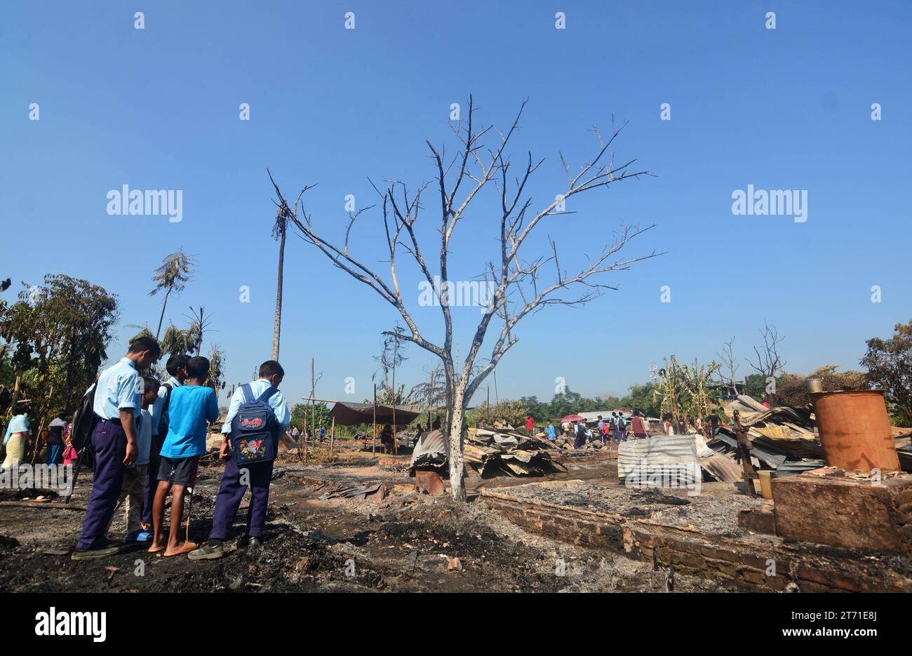 Dimapur, India: 13 de noviembre de 2023: Estudiante de escuela mira entre una casa carbonizada después de un infierno en la noche de Diwali, la celebración del Festival Hindú de la Luz, que destruyó al menos 50 casas matando a 5 personas en Naharbari en Dimapur, India, estado nororiental de Nagaland. Crédito: Caisii Mao/Alamy Live News Foto de stock