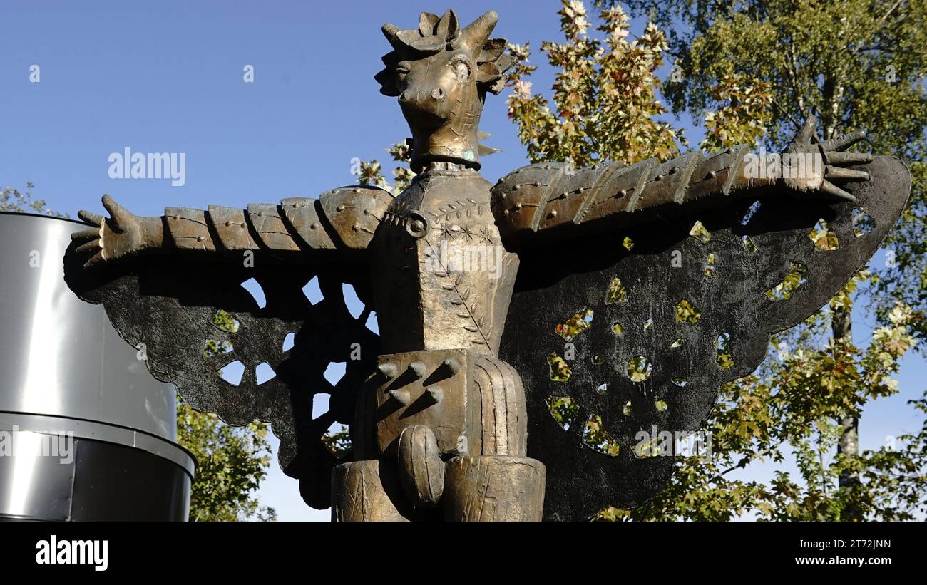 Una estatua de piedra envejecida de un guerrero con un arma en la mano se encuentra en un pedestal en un campo cubierto de hierba Foto de stock