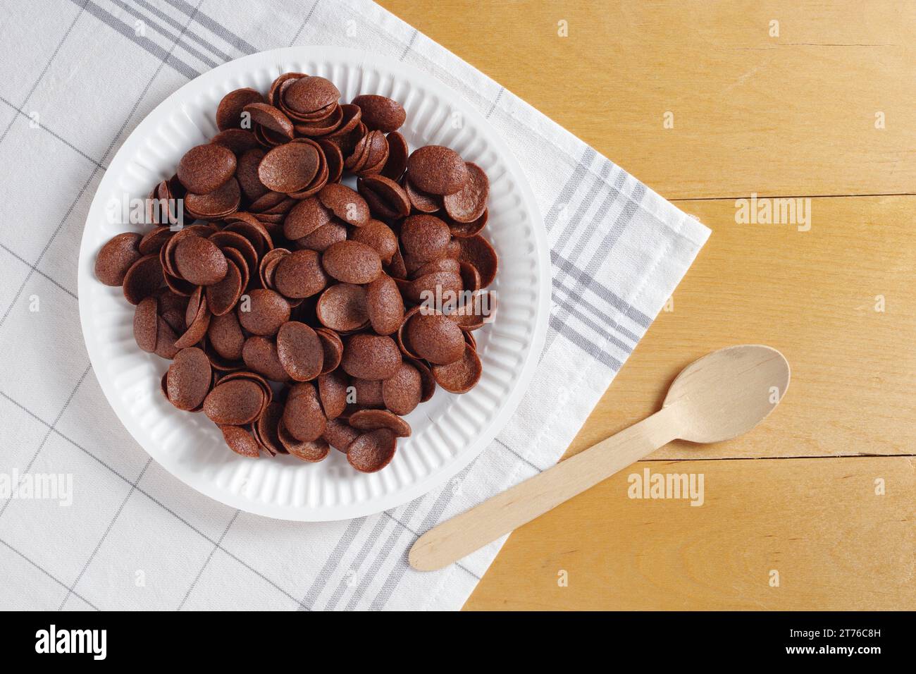 Directamente encima de la vista del desayuno de cereales de chocolate en plato desechable de cartón sobre mesa de madera Foto de stock