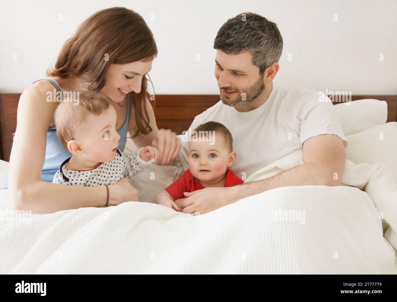 Pareja en la cama con su bebé gemelos Foto de stock