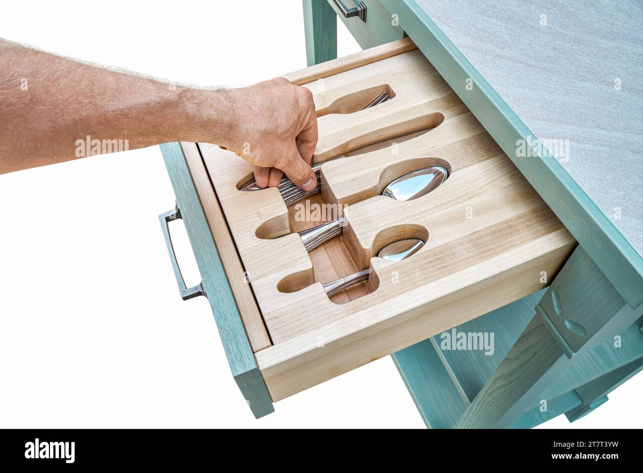 La mano del hombre pone el cuchillo en el tenedor de madera anhelado en el cajón del gabinete de cocina de cerca. La persona toma cubiertos de la bandeja de almacenamiento. Muebles para el hogar Foto de stock