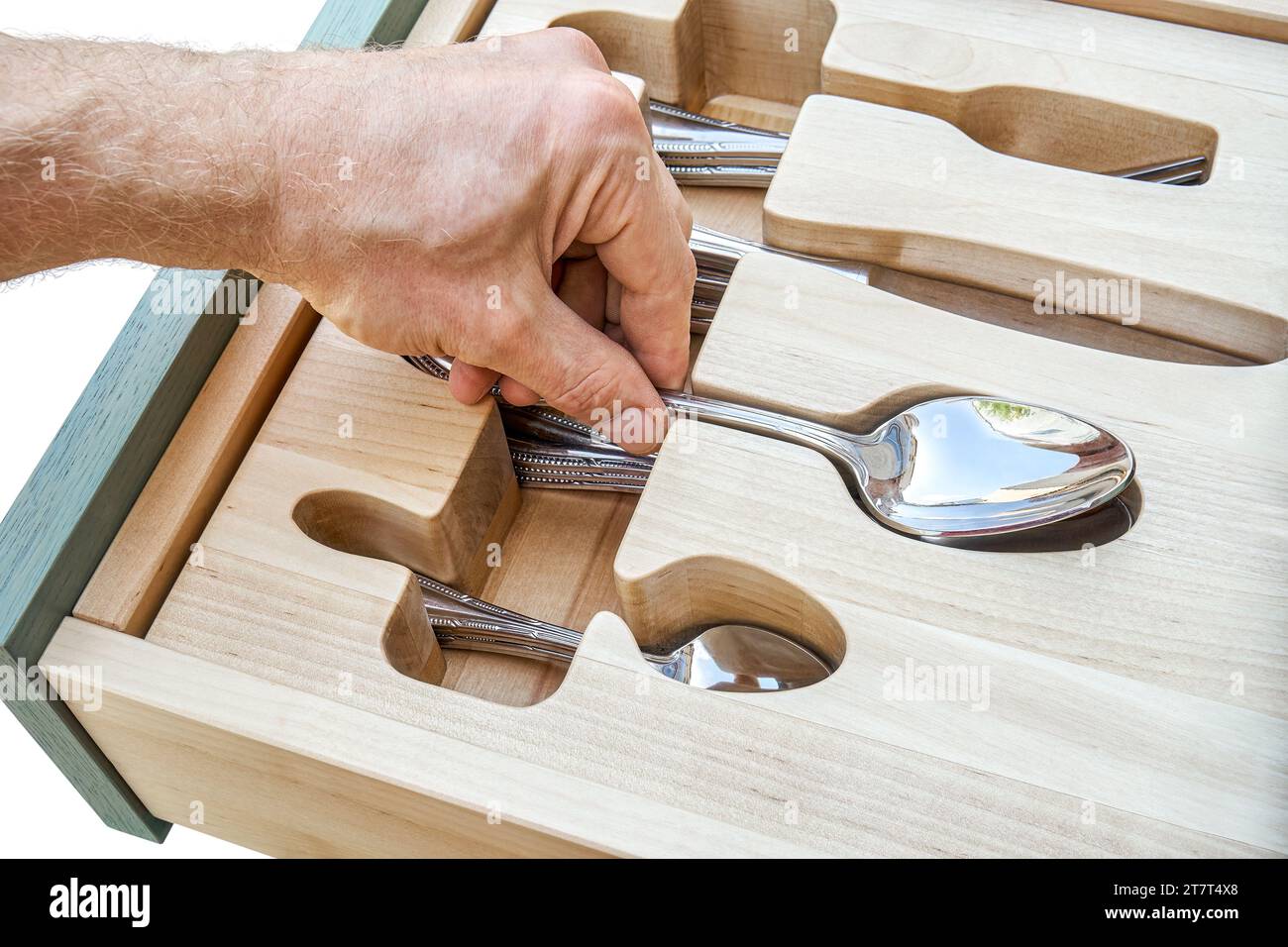 La mano del hombre pone cuchara en el soporte de madera anhelado en el cajón del gabinete de cocina de cerca. La persona toma cubiertos de la bandeja de almacenamiento. Muebles para el hogar Foto de stock