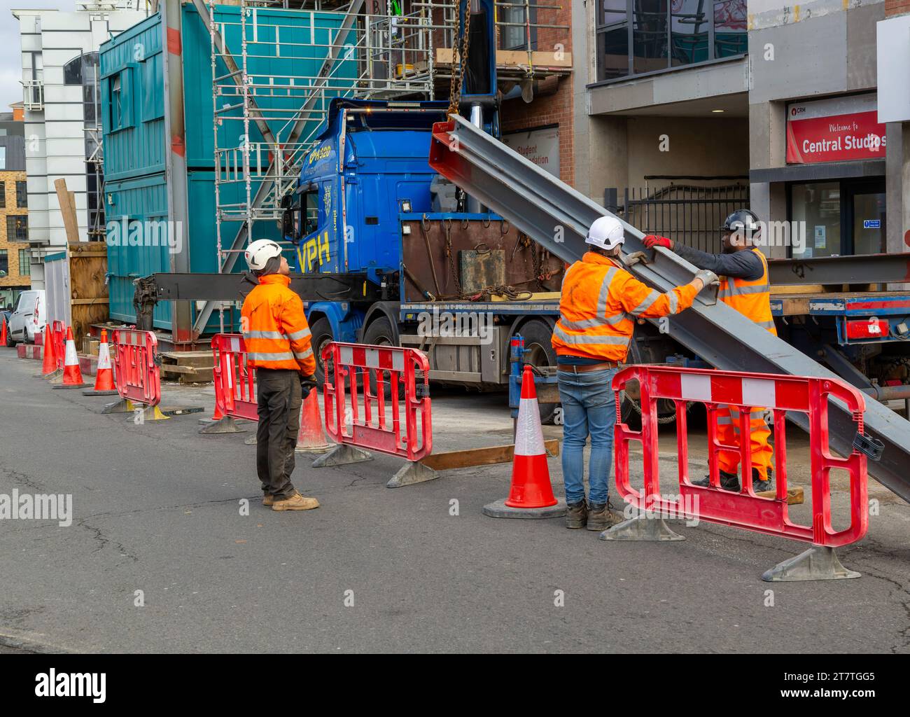 Trabajadores y grúa trabajando con viga de acero en la calle, Reading, Berkshire, Inglaterra, Reino Unido Foto de stock