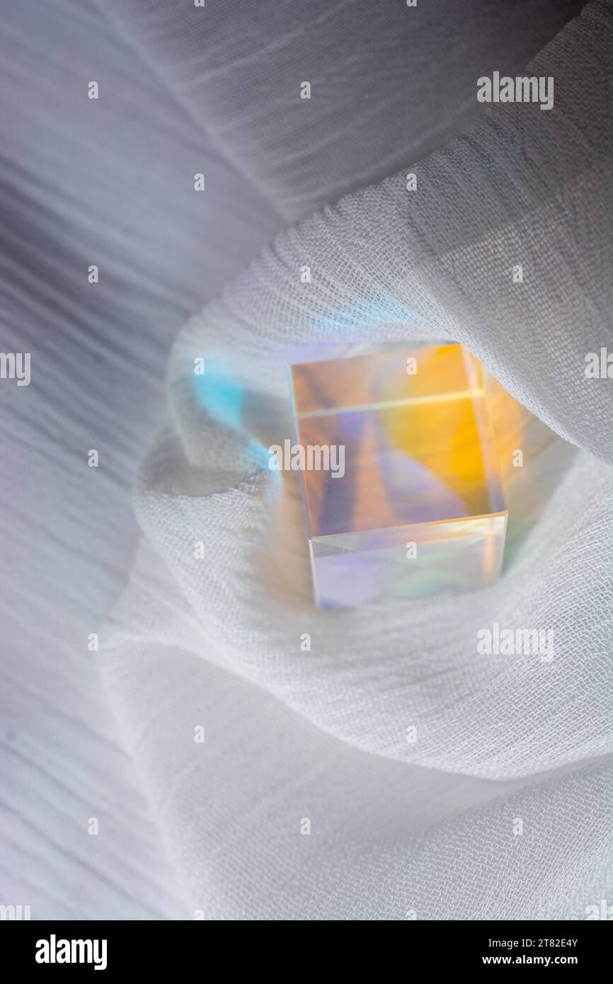 Cubo de vidrio con rayos de espectro de color en la tela. Fondo abstracto con reflexión y refracción de la luz Foto de stock