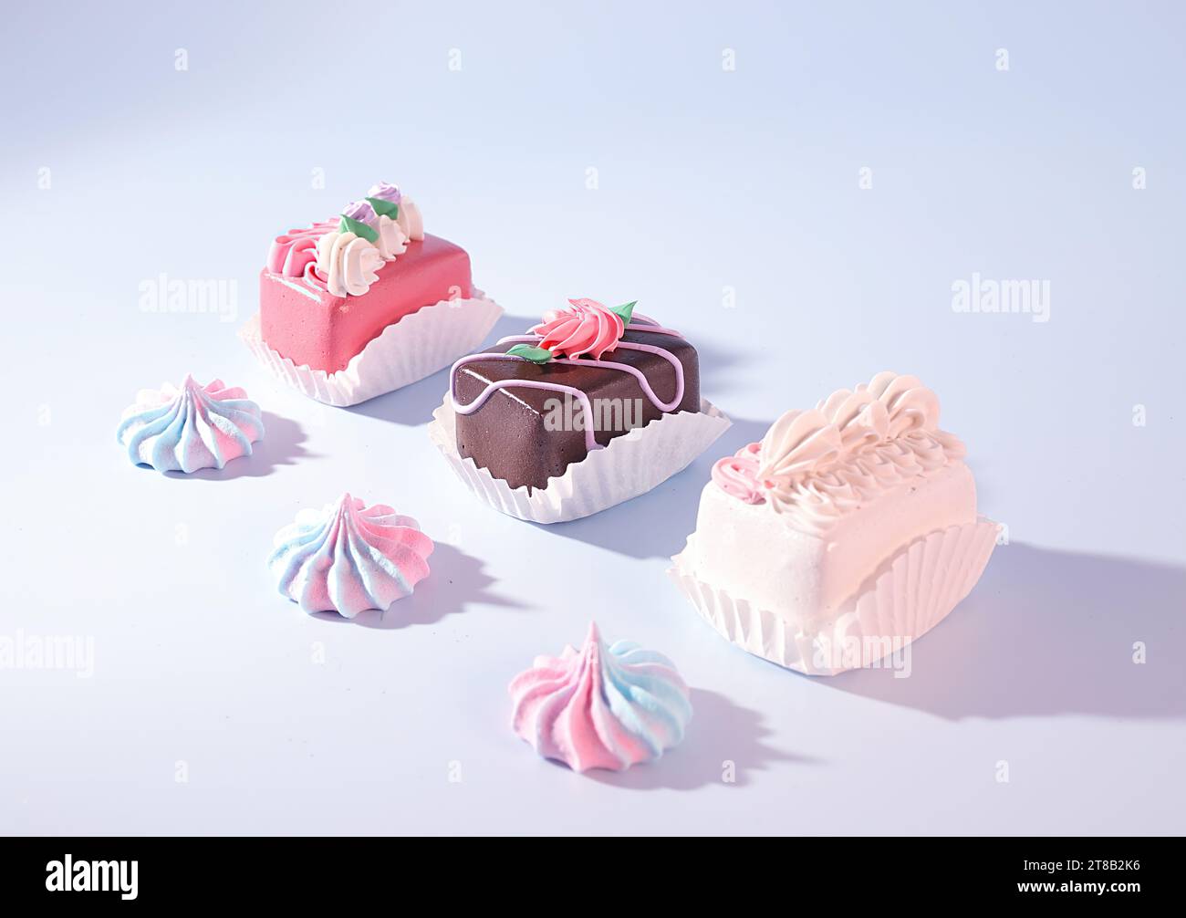 Mini Petite cuatro pasteles decorados y merengue caramelo sobre fondo azul, golosinas de Pascua, concepto de panadería, postres Foto de stock