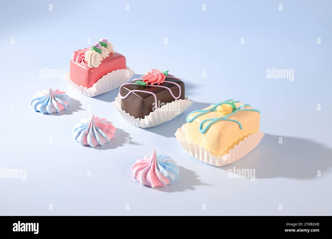 Mini Petite cuatro pasteles decorados y merengue caramelo sobre fondo azul, golosinas de Pascua, concepto de panadería Foto de stock