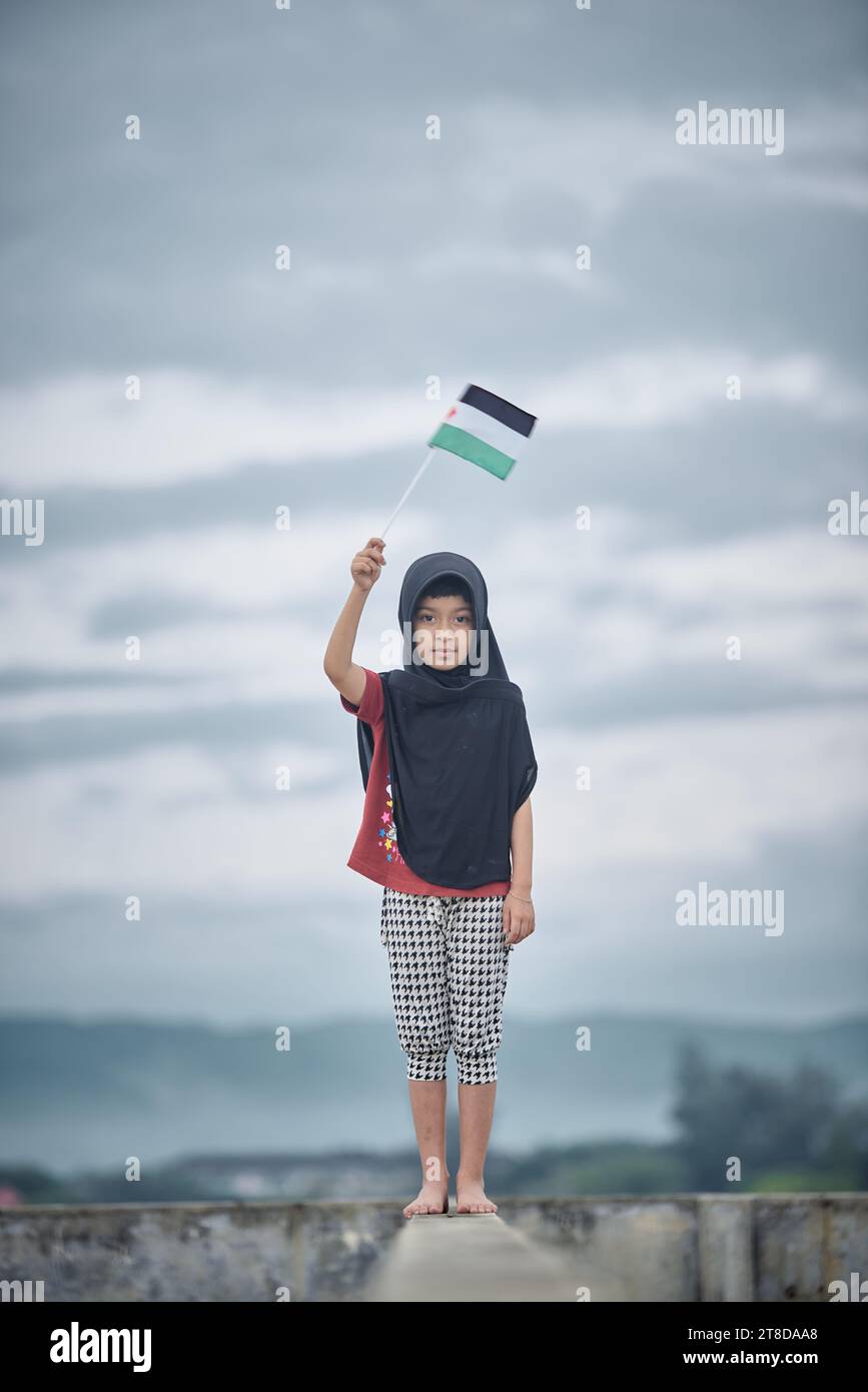 Linda niña ondeando bandera palestina envía un poderoso mensaje de apoyo y empatía al mundo Foto de stock