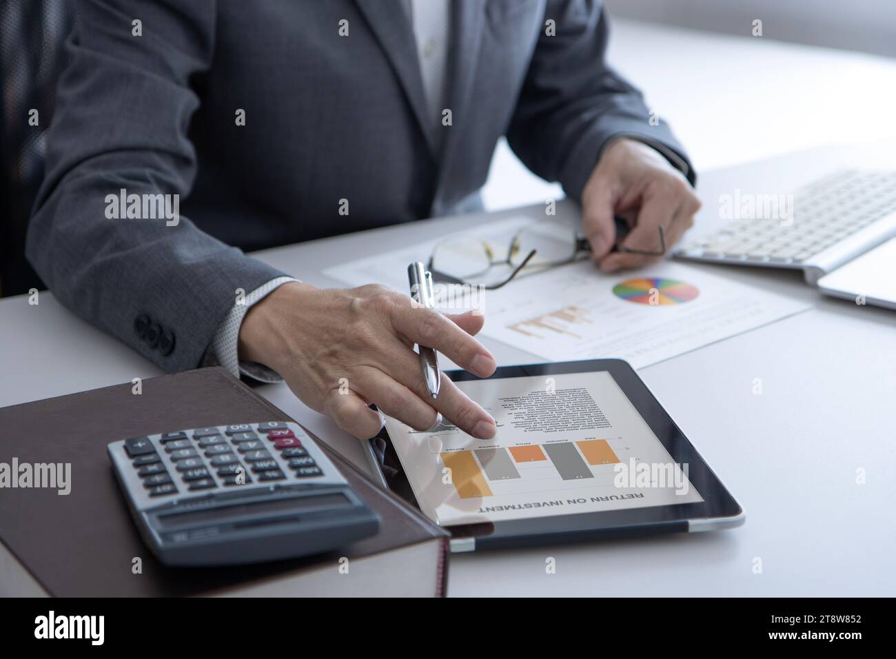 Hombre de negocios en la oficina tabbing en la pantalla de la tableta mientras que revela el rendimiento del negocio para el retorno de la inversión Foto de stock