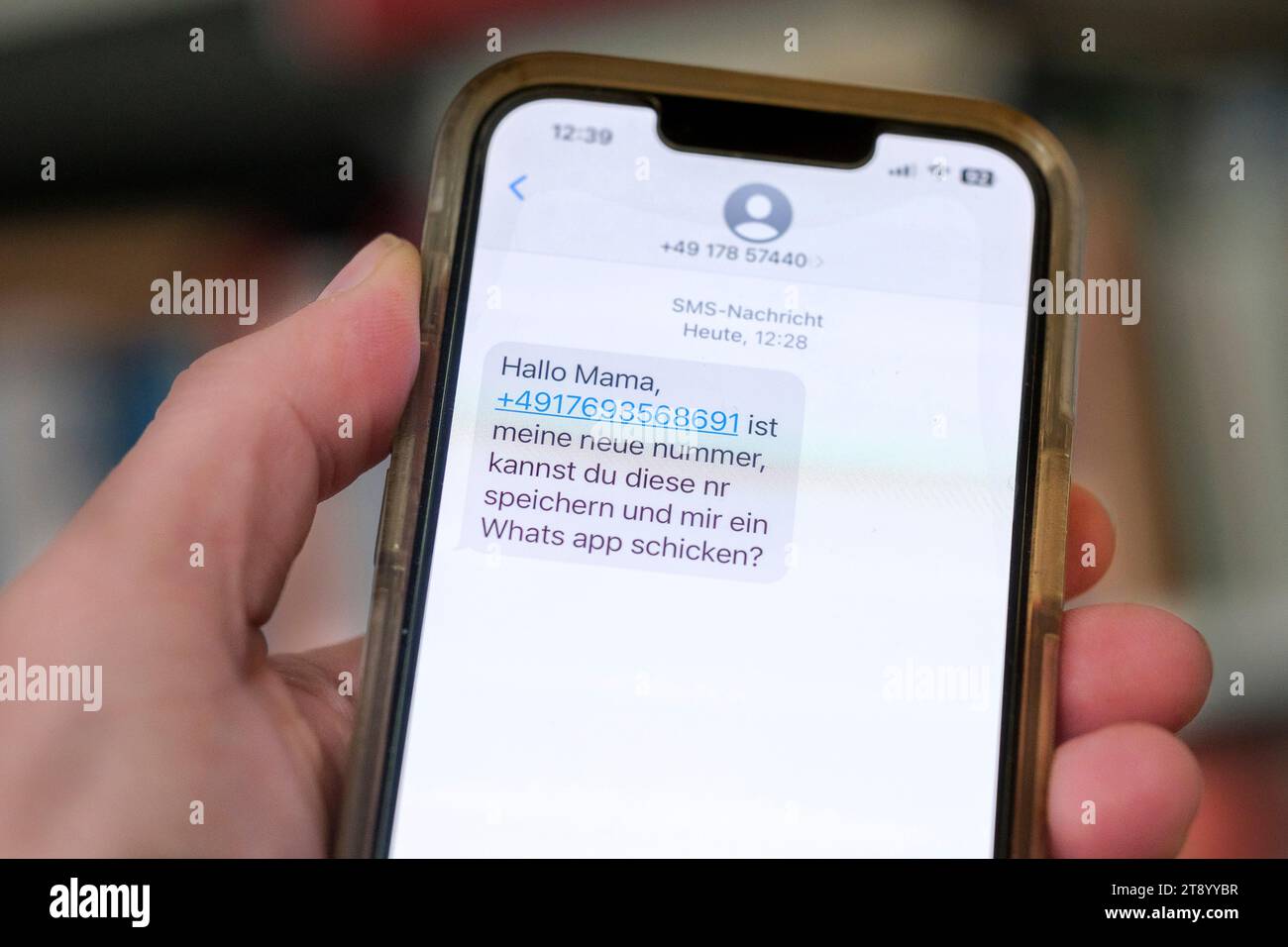 Mano sostiene un teléfono móvil con un mensaje de WhatsApp, que es el comienzo de un caso de estafa de mensajería Foto de stock