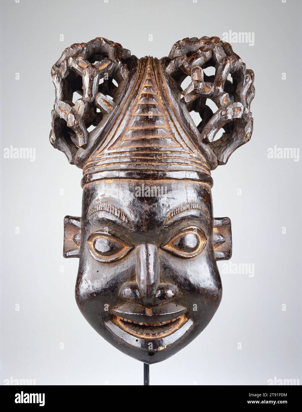 Máscara, siglo XX, 21 x 14 1/4 x 11 1/4 in. (53,3 x 36,2 x 28,6 cm), Madera, Camerún, siglo XX, esta máscara de casco es parte de un grupo de máscaras de linaje, o una familia de máscaras que actúan juntas. Representa el rostro humano masculino y simboliza un antepasado real o de clan. Máscaras como estas suelen actuar en funerales o celebraciones conmemorativas. Esta máscara se usa en la parte superior de la cabeza, mientras que un velo de malla oculta la cara del artista Foto de stock