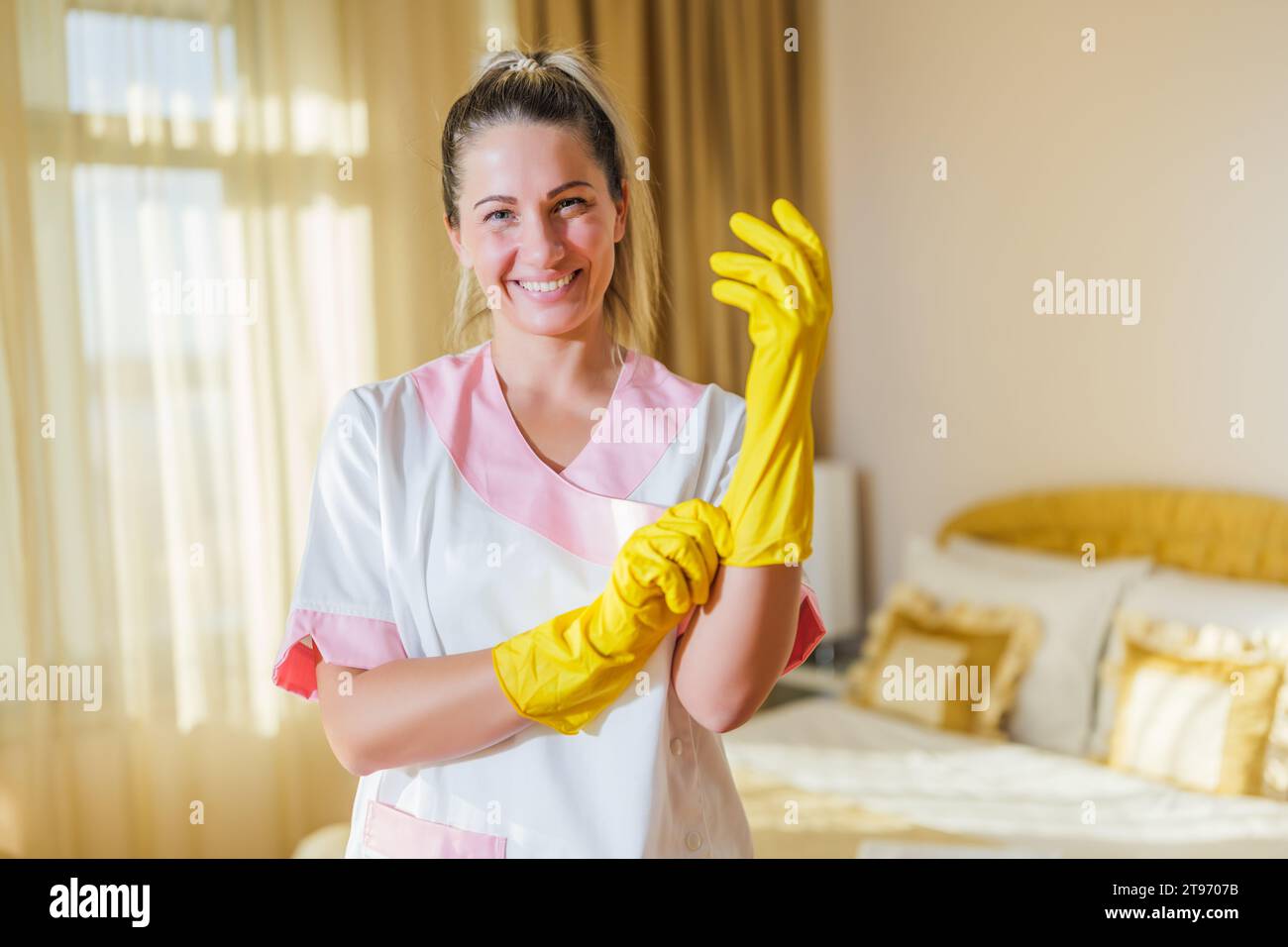 Retrato de la hermosa criada del hotel con guantes de lavado. Foto de stock