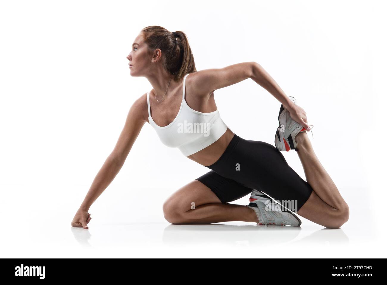 Ajuste fuerte mujer de fitness en ropa deportiva estirar las piernas sobre  fondo blanco aislado. Instructora de deporte femenina haciendo ejercicio  físico Fotografía de stock - Alamy