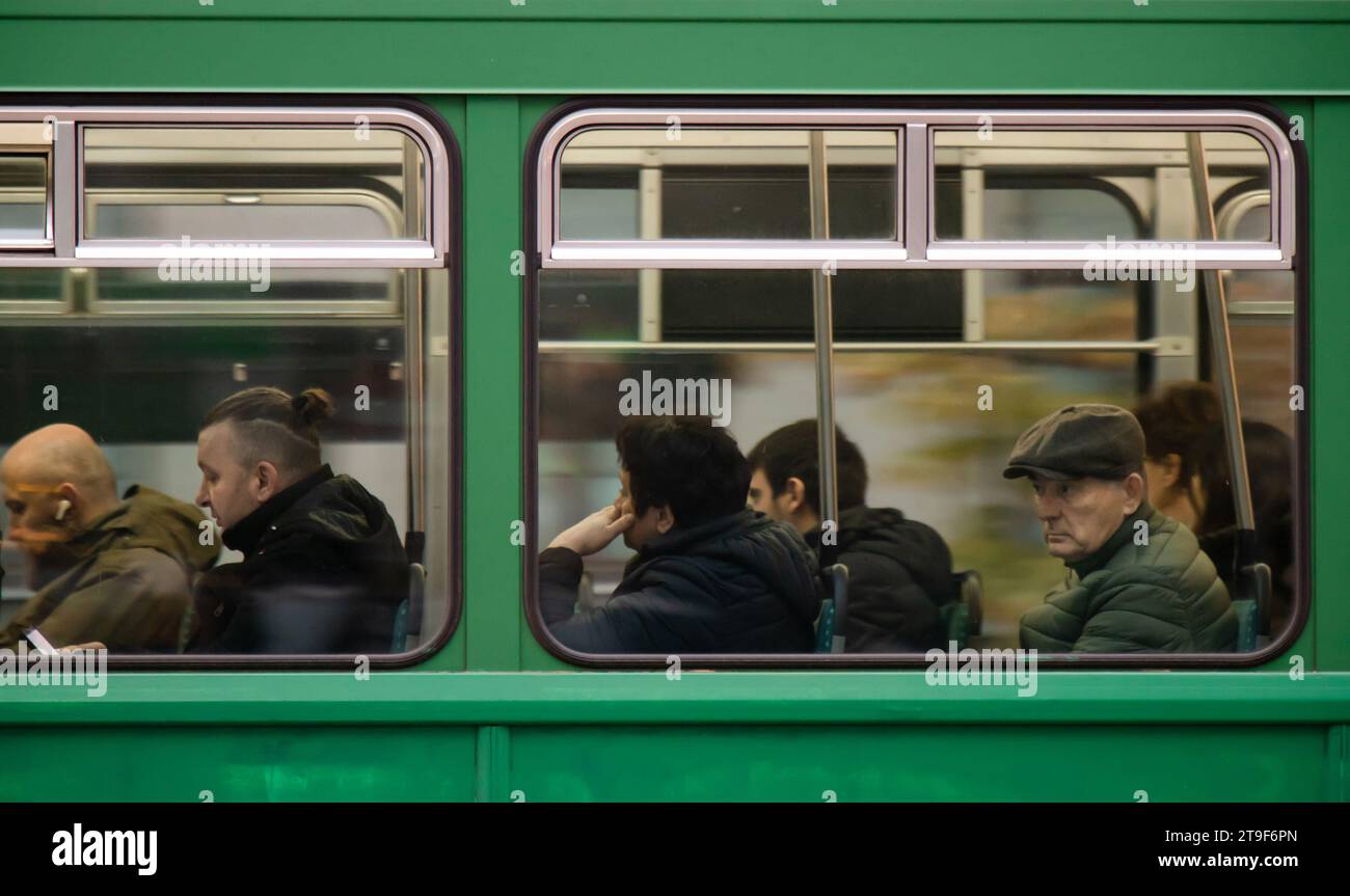 Belgrado, Serbia - 23 de noviembre de 2023: Personas, hombres sentados en los asientos de las ventanas mientras viajan en un tranvía verde de transporte público en un día de otoño Foto de stock