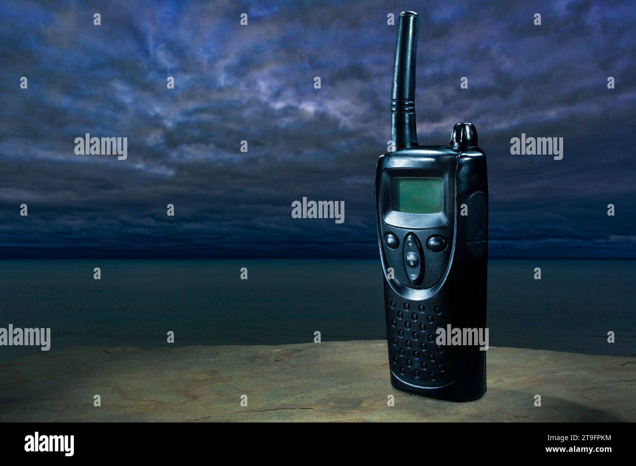 Walkie-talkie con una pantalla en blanco para texto y espacio de copia desde el océano con nubes de tormenta que se reúnen. Foto de stock