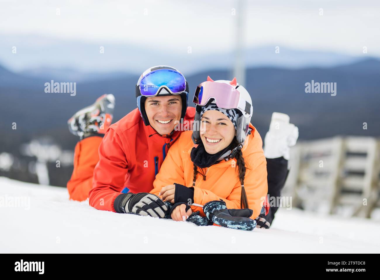 Desde arriba de un niño feliz con ropa abrigada y gafas de esquí  descansando sobre la nieve blanca con los brazos levantados