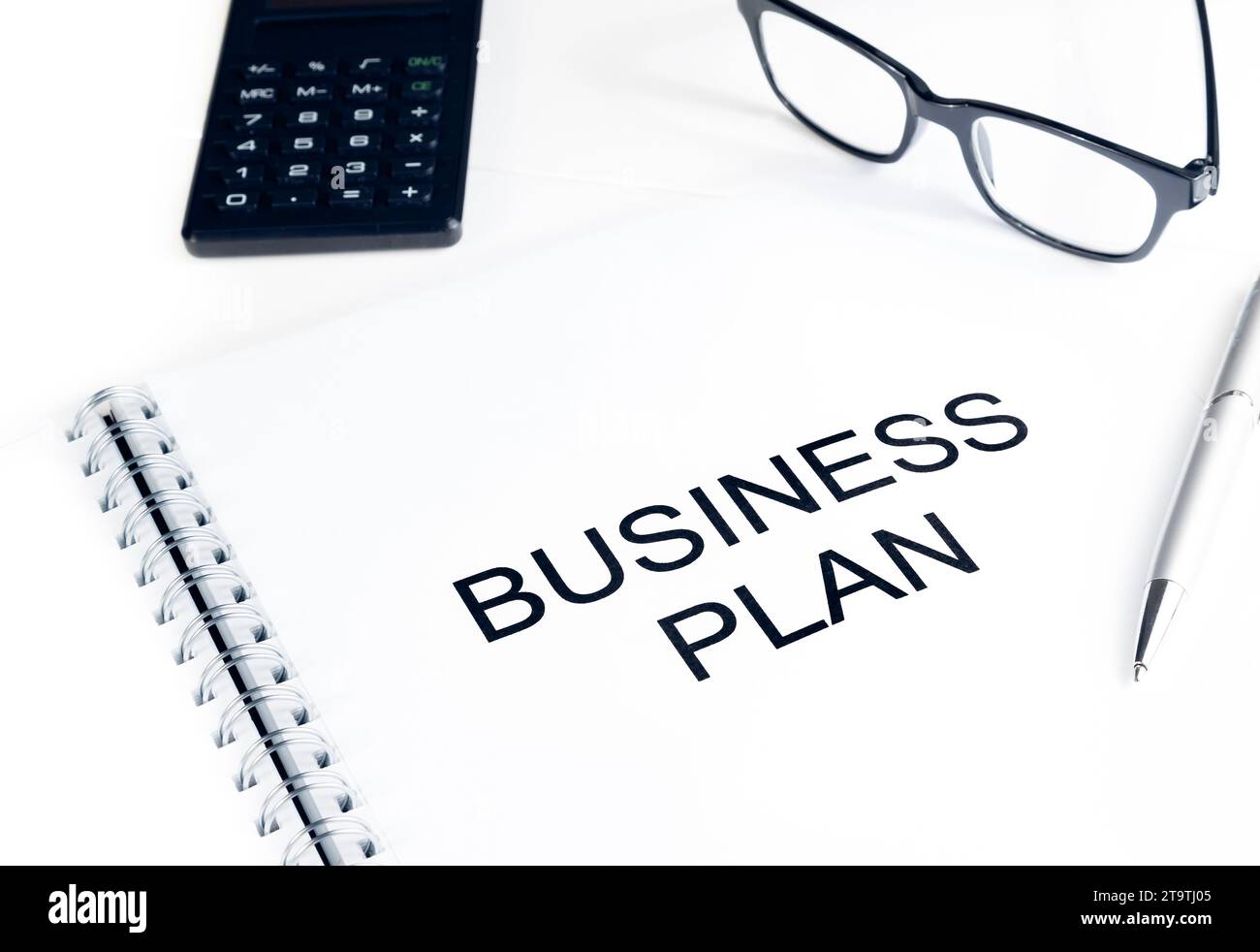 palabras de plan de negocios cerca de la calculadora, gafas y pluma en la mesa, concepto de negocio Foto de stock