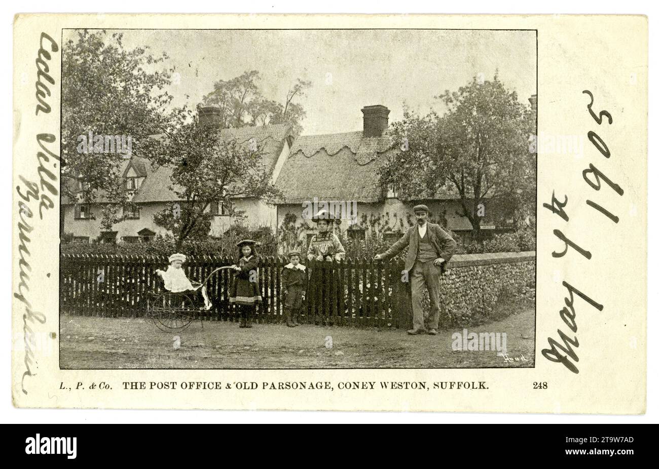 Postal eduardiana original de la oficina de correos y Parsonage, Coney Weston, Suffolk, una pose de familia respetable fuera de la puerta principal, un niño empuja un cochecito, posiblemente el maestro de correos o la posama. Una escena típica de principios de los años 1900 en la Inglaterra rural. Postal fechada el 7 de mayo de 1905 en la parte delantera. Suffolk, Inglaterra, Reino Unido Foto de stock