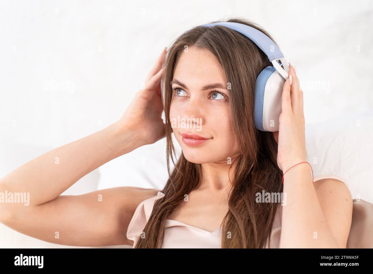 Relajarse en la cama en un día libre. Meditación con auriculares como una forma de relajarse y restaurar la energía. Chica escucha la meditación de la música usando headpho inalámbrico Foto de stock