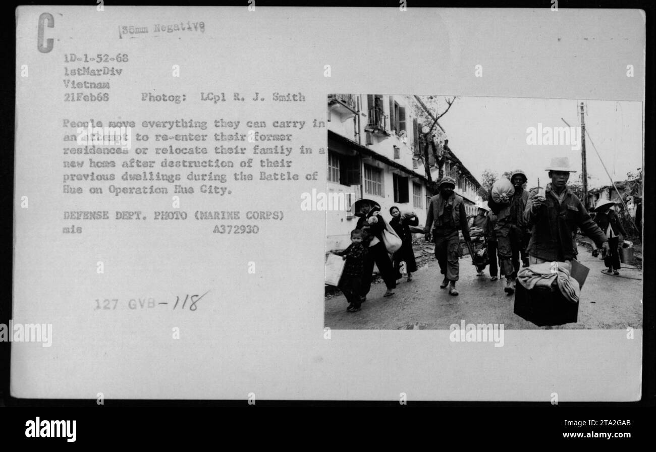 La imagen muestra a civiles vietnamitas llevando sus pertenencias mientras intentan volver a entrar en sus casas destruidas o encontrar nuevos lugares para vivir después de la Batalla de Hue en la Operación Ciudad Hue durante la Guerra de Vietnam. La foto fue tomada el 21 de febrero de 1968 por LCpl R. J. Smith de la 1ª División de Marines. Foto de stock