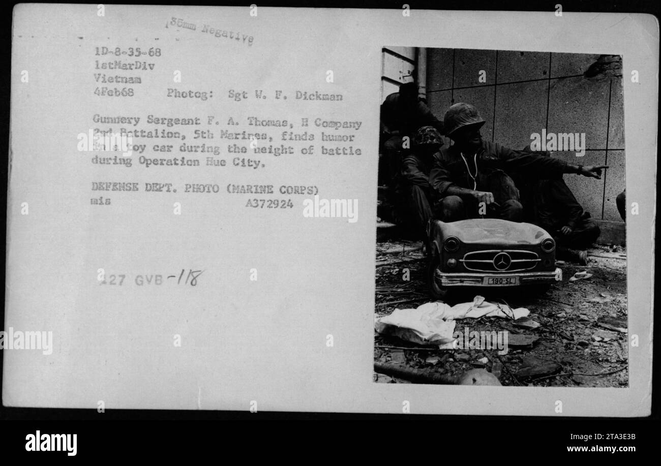 El Sargento Gunnery F. A. Thomas de la Compañía H, 2do Batallón, 5to Infantería de Marina, encuentra humor en un auto de juguete durante la intensa batalla de la Operación Ciudad Hue. Esta fotografía fue tomada el 4 de febrero de 1968 por el Sargento W. F. Dickman y es parte de la colección negativa de 35 mm del Departamento de Defensa de los Estados Unidos. Foto de stock