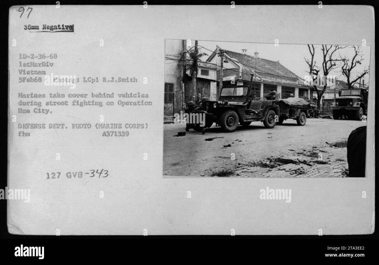 Los infantes de marina buscan refugio detrás de varios vehículos durante los combates callejeros de la Operación Ciudad Hue el 5 de febrero de 1968. Esta fotografía muestra una amplia gama de vehículos, incluyendo jeeps, "mulas", camiones y buggies de dunas utilizados por el personal militar estadounidense durante la Guerra de Vietnam. Foto de stock