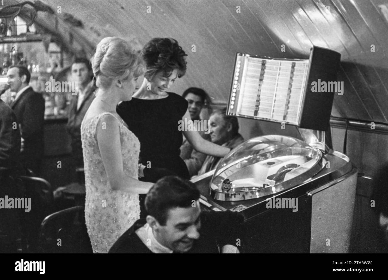 La actriz Caron Gardner y su amiga seleccionan música en una jukebox en un club londinense en 1961, mientras cumple con sus deberes como Miss London After Dark Foto de stock