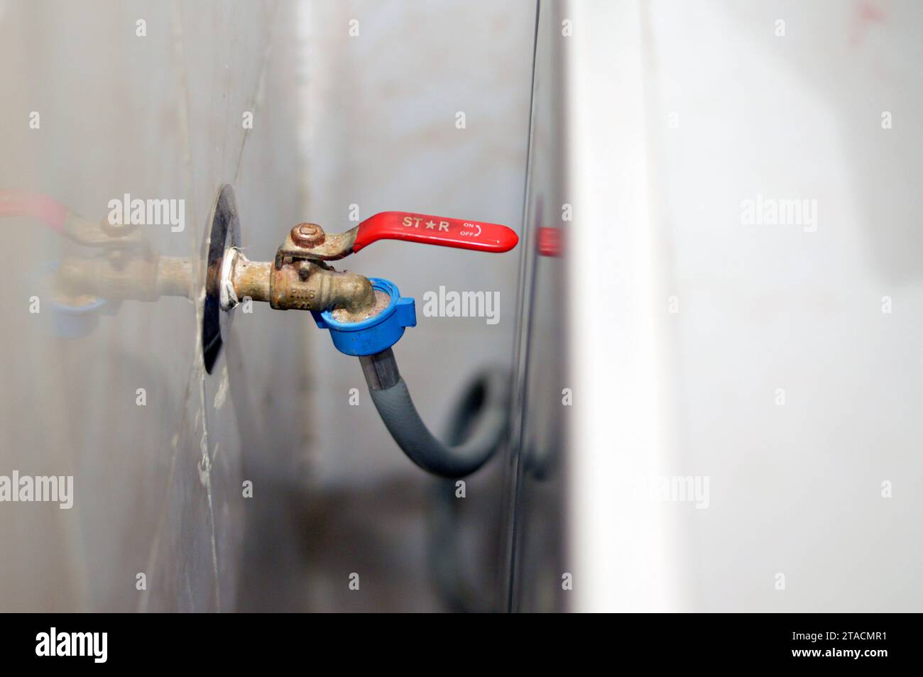 El Cairo, Egipto, 9 de octubre de 2023: Grifo de lavadora estrella con tubo de manguera de agua para el suministro de agua a la válvula de entrada de agua, mantenimiento y electrodomésticos Foto de stock