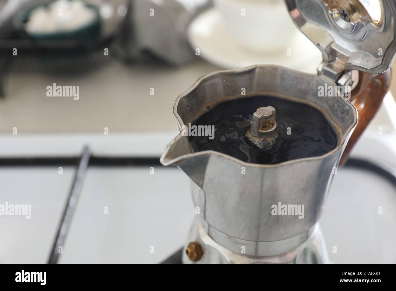 Cafetera italiana de moca sobre la estufa humeando vapor y aroma