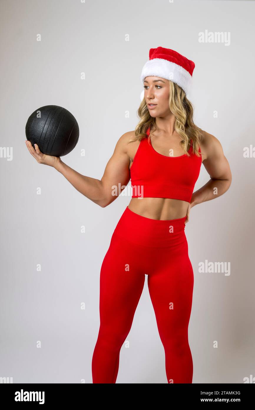 Bodybuilder Femenino Leggings Rojos y Deportes Sujetador Santa Hat Xmas Trabajando Bola de Medicina Foto de stock