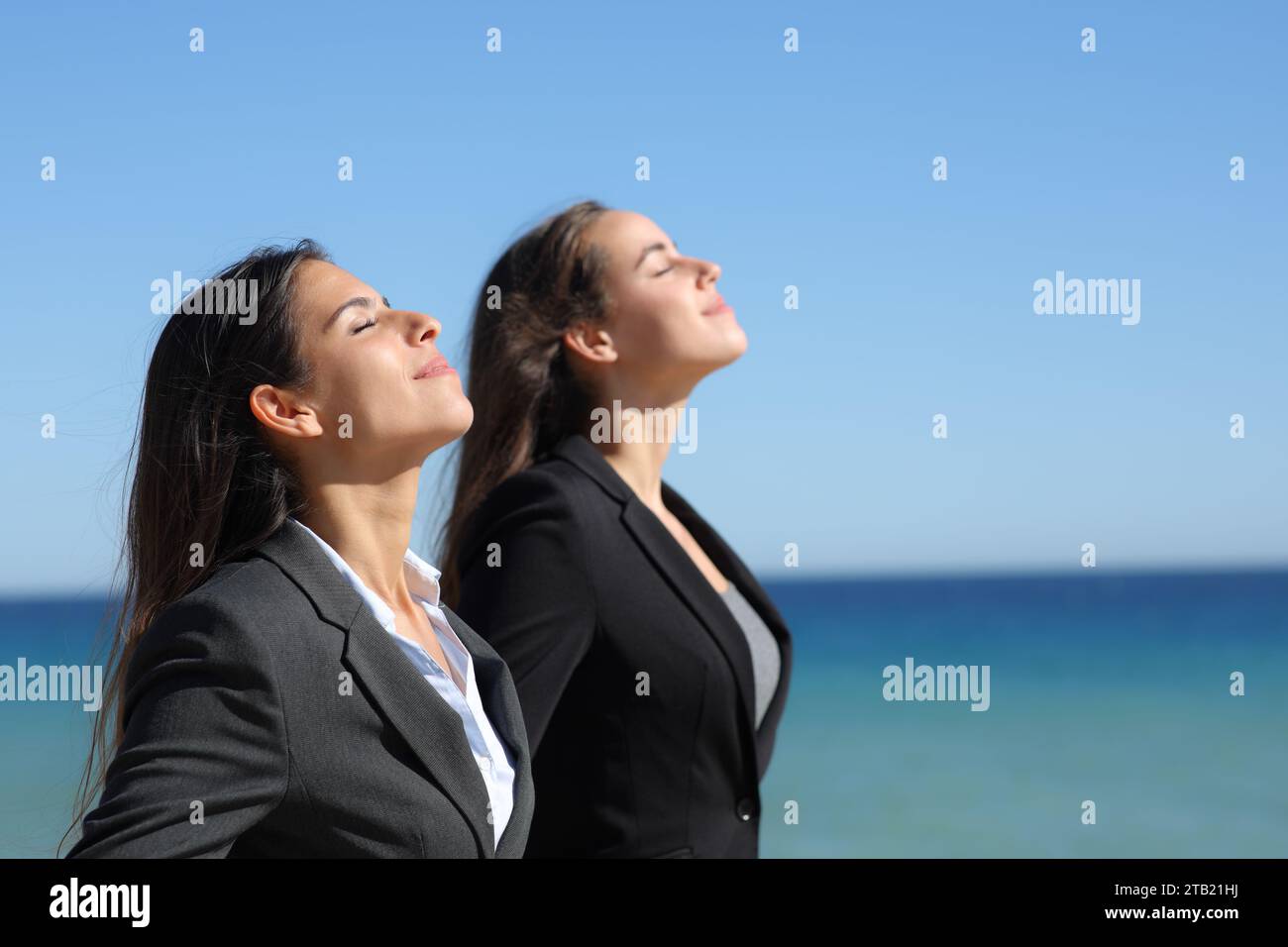 Perfil de dos ejecutivos relajándose respirando aire fresco en la playa Foto de stock