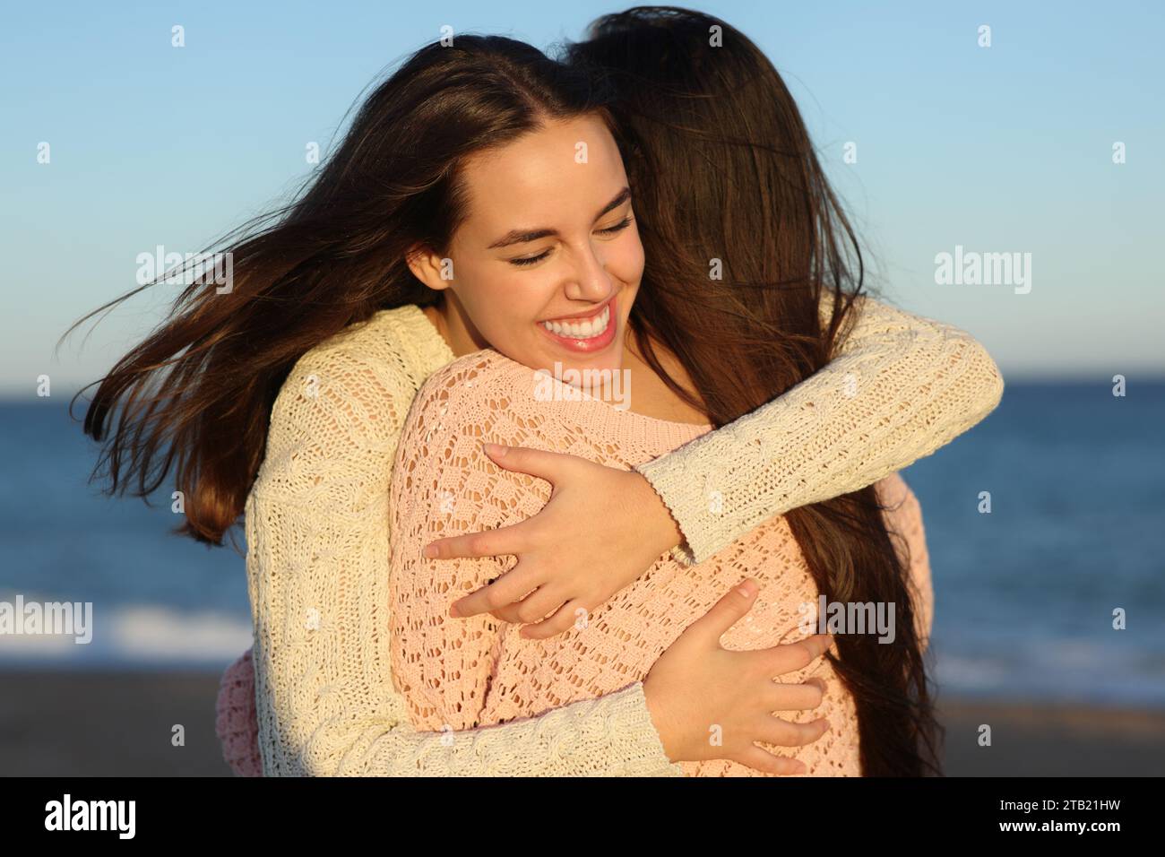 Dos amigos felices abrazando cariñosos al atardecer en la playa Foto de stock