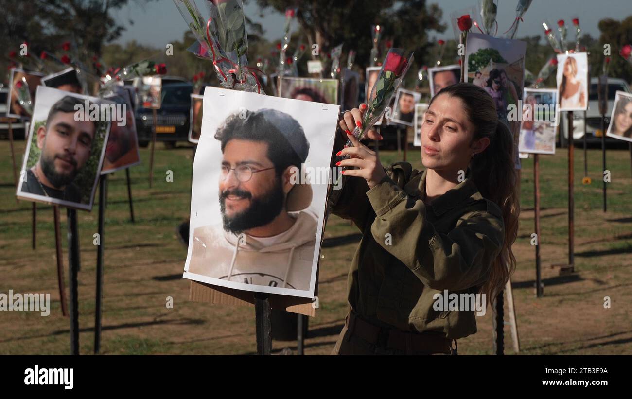 Un soldado israelí coloca una rosa mientras rinde sus respetos en una instalación con las fotos de los asistentes al festival israelíes que fueron asesinados durante el ataque del 7 de octubre por militantes de Hamás de la Franja de Gaza en el lugar del festival de música Supernova el sexto día de la semana una tregua entre Israel y Hamás el 28 de noviembre de 2023 en Re'im, Israel. Israel y Hamas acordaron una prórroga de dos días de su tregua inicial de cuatro días, que prometía la liberación de más rehenes israelíes retenidos en Gaza, así como la liberación de prisioneros palestinos retenidos en cárceles israelíes Foto de stock