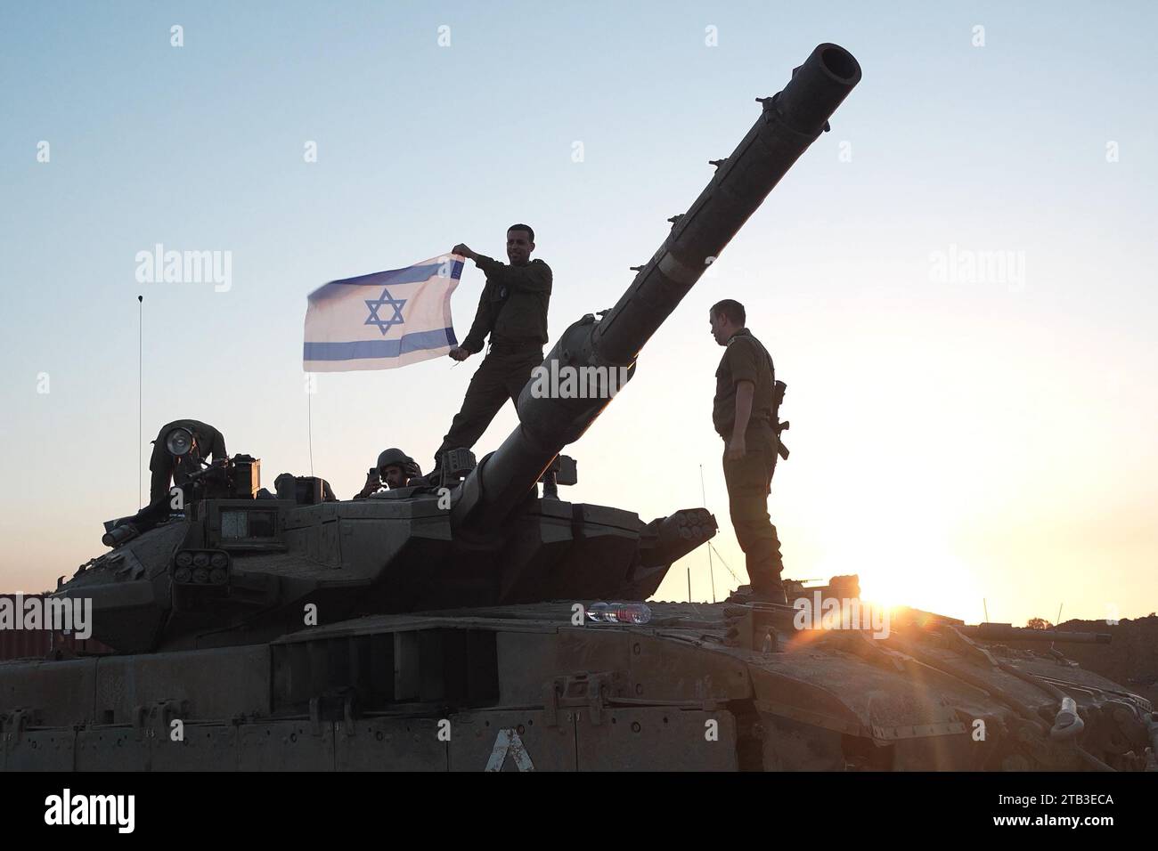 Soldados israelíes sostienen una bandera israelí mientras se paran en un tanque desplegado cerca de la frontera con la Franja de Gaza después de regresar de Gaza el sexto día de una tregua entre Israel y Hamás el 28 de noviembre de 2023 en Be'eri, Israel. Israel y Hamas acordaron una prórroga de dos días de su tregua inicial de cuatro días, que prometía la liberación de más rehenes israelíes retenidos en Gaza, así como la liberación de prisioneros palestinos retenidos en cárceles israelíes. Foto de stock