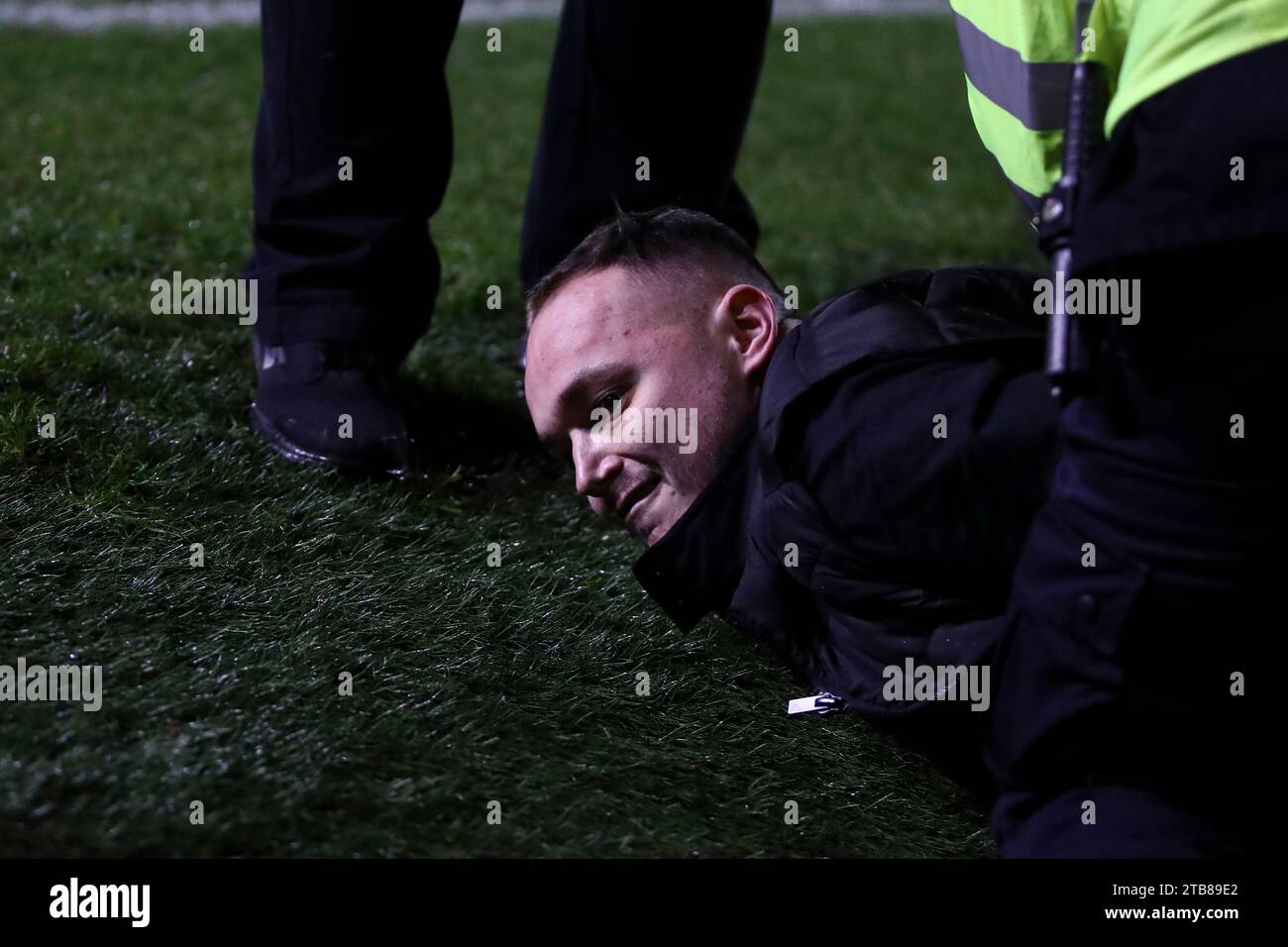 Wimbledon, Reino Unido. 4 de diciembre de 2023. Un invasor de la cancha en el suelo después de ser arrestado durante el partido de la segunda ronda de la Copa FA entre AFC Wimbledon y Ramsgate en Plough Lane, Wimbledon el lunes 4 de diciembre de 2023. (Foto: Tom West | MI News) Crédito: MI News & Sport /Alamy Live News Foto de stock