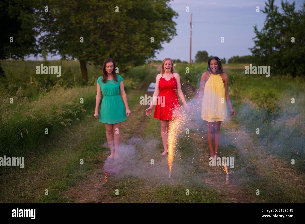 Tres mujeres jóvenes en ropa de formalwear galletas ligeras en el campo; Bennet, Nebraska (Estados Unidos de América) Foto de stock