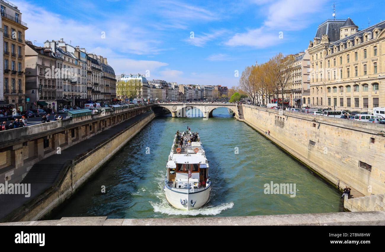 Francia, 5 de abril de 2019: Hermoso paisaje urbano de París, puente de Saint-Michel a través del río Sena y un barco turístico con turistas Foto de stock