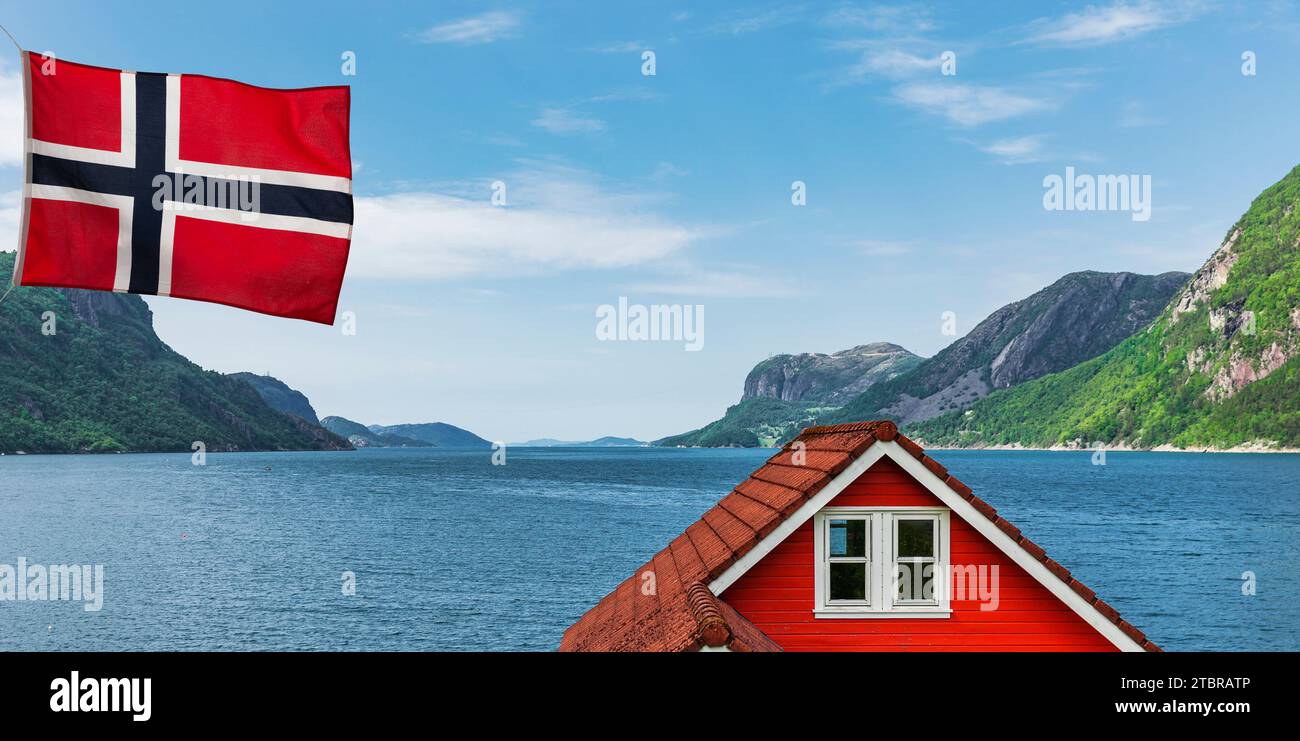Casa roja en un fiordo en Noruega con bandera Foto de stock