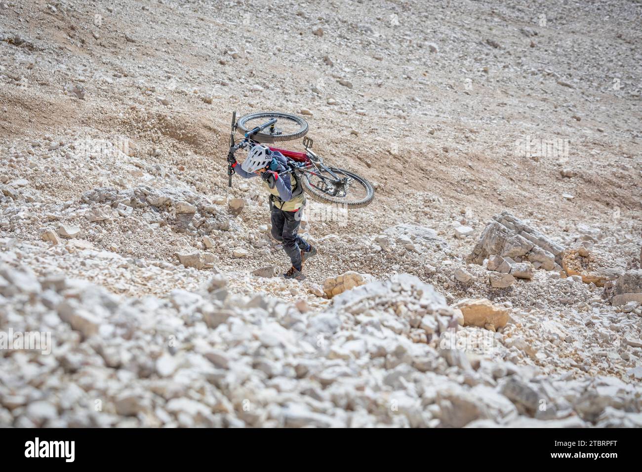 Italia, Dolomitas, ciclista de montaña en un sendero alpino llevando la bicicleta de montaña en su espalda en una sección muy difícil Foto de stock