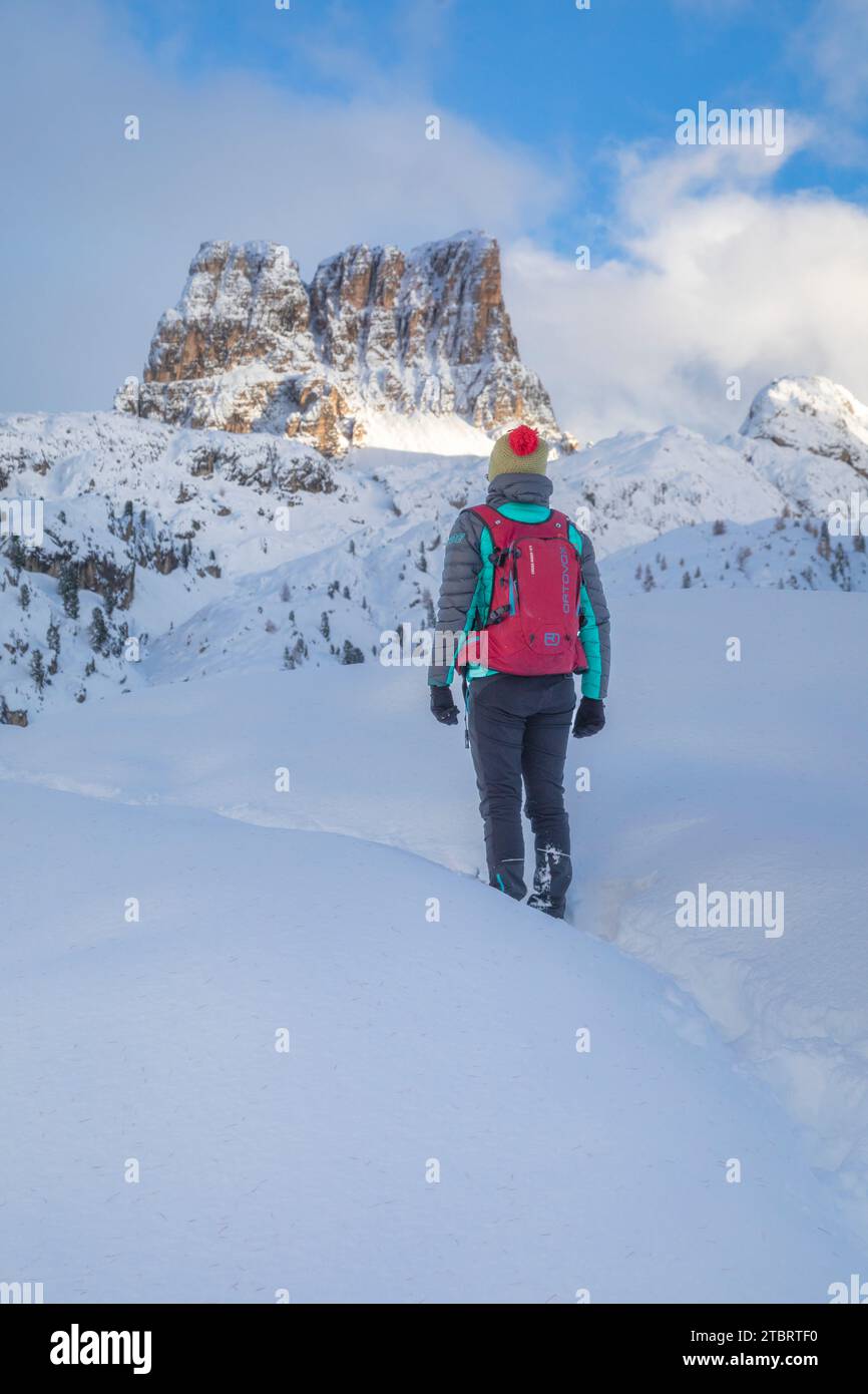 Italia, Véneto, provincia de Belluno, zona de Falzarego, excursionista en un paisaje de invierno con nieve fresca parado y observando la montaña Averau en el fondo, Dolomitas Foto de stock