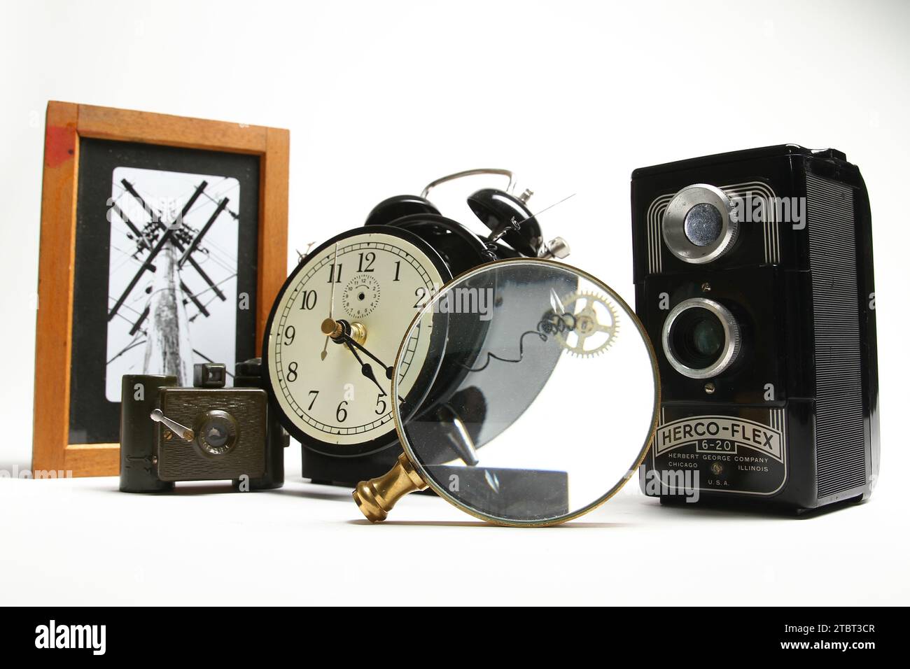 Cámaras vintage, reloj despertador desmontado y lupa sobre fondo blanco Foto de stock