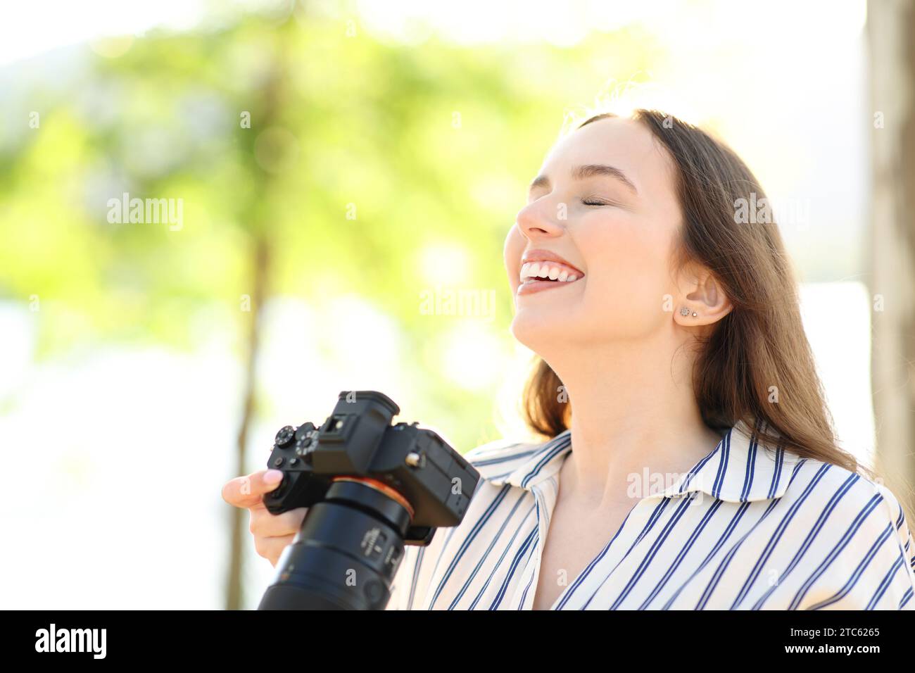 Fotógrafo feliz respirando aire fresco de pie en la montaña Foto de stock