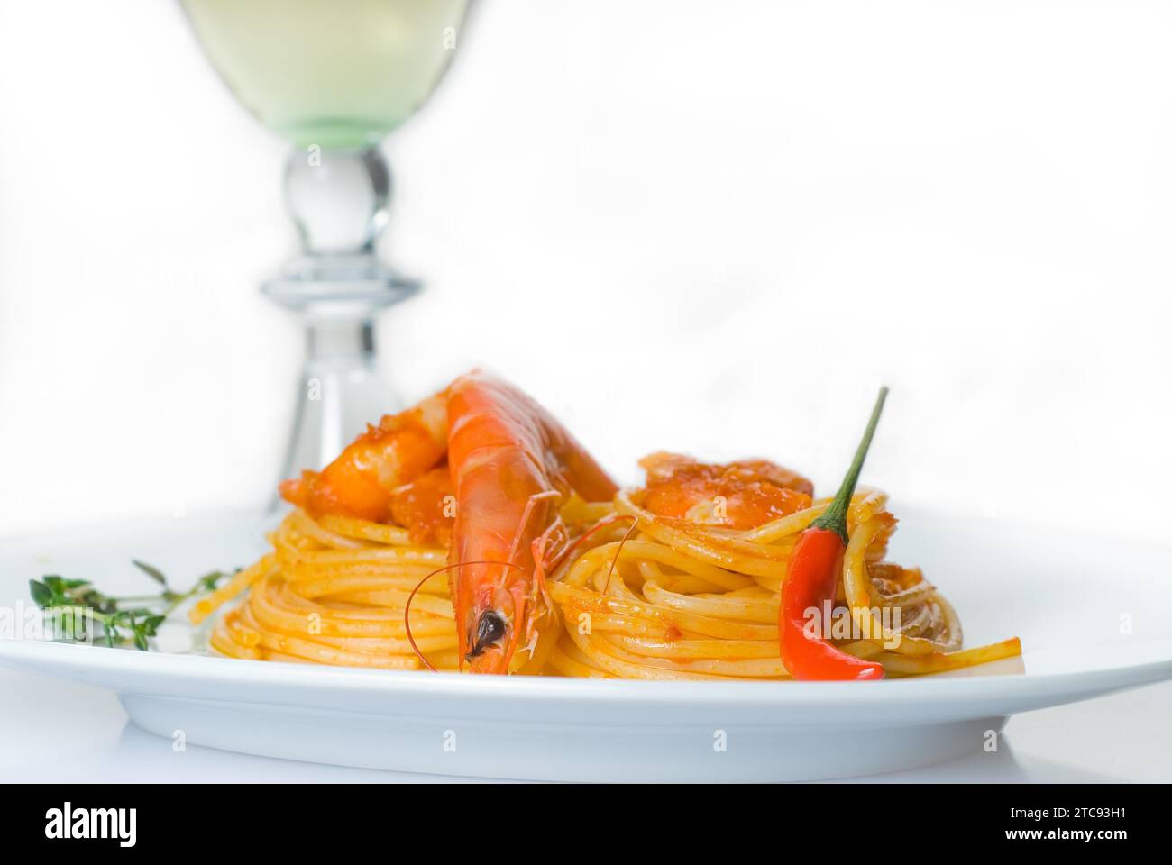 Pasta de espagueti italiana y salsa de camarones picantes frescos, con una hierba de vino blanco seco en el fondo Foto de stock