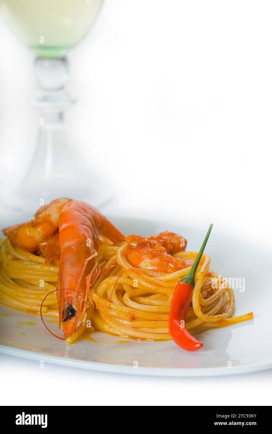 Pasta de espagueti italiana y salsa de camarones picantes frescos, con una hierba de vino blanco seco en el fondo Foto de stock