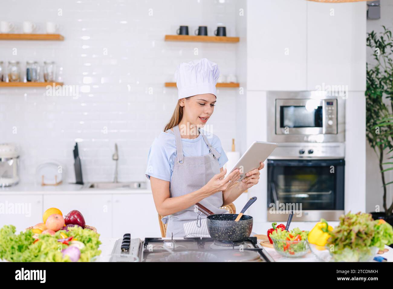 mujer en línea que aprende cocinar de la tableta en la cocina casera gente moderna con el concepto de estilo de vida de la tecnología Foto de stock